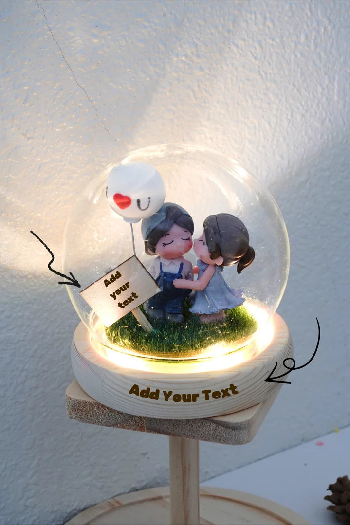 Decorative figurine with a couple under a glass dome on a white background and warm light base