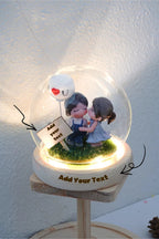 Decorative figurine with a couple under a glass dome on a white background and warm light base