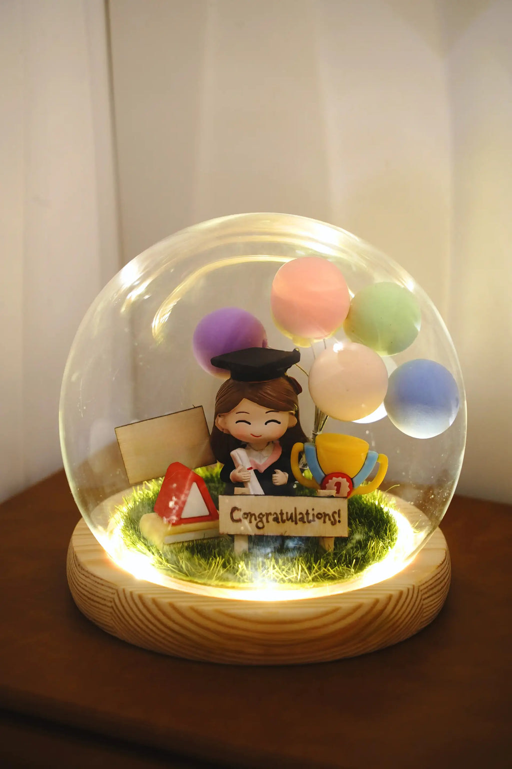 Crystal ball featuring proud sister graduate miniature under round glass dome with customizable wooden base